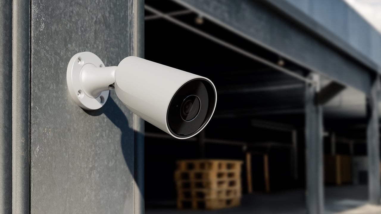 A white bullet-style CCTV camera mounted at a Brisbane warehouse facility.