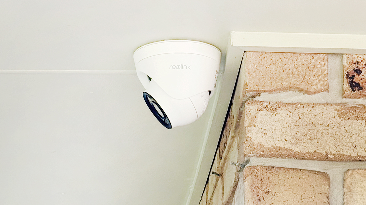Reolink turret-style security camera installed on a Springwood home ceiling near a brick wall.